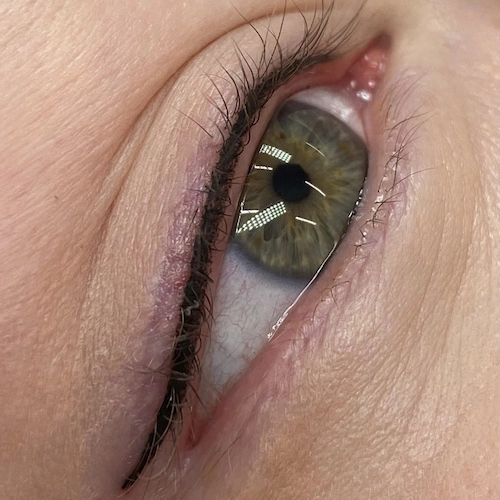Zbliżenie na oko po  wykonanym zabiegu makijażu permanentnego oczu metodą kreska w linii rzęs